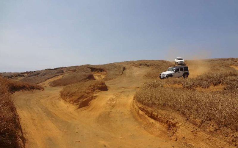 Jeep driving on a dirt road to the beach